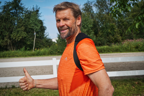 Lächelnder Mann im Sport-T-Shirt trägt das MT-Band und zeigt den Daumen nach oben